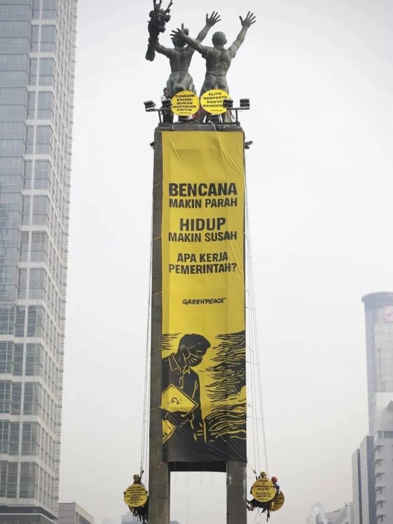 Aktivis Greenpeace membentangkan spanduk kritik di Bundaran HI